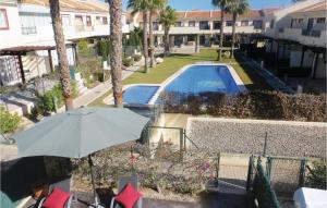 a person sitting under an umbrella next to a swimming pool at 2 Bedroom Cozy Home In Ciudad Quesada in Ciudad Quesada +11 photos