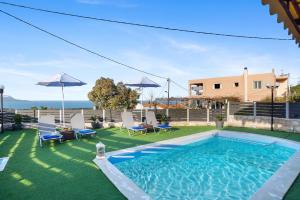 a pool with chairs and umbrellas in a yard at Nikos Dimitra Luxury Home BY APOKORONAS-VILLAS in Plaka