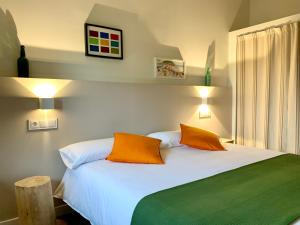 a bedroom with a white bed with two orange pillows at EL PILPAYO in Quintes