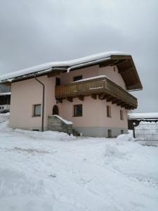 a house covered in snow with a balcony at Grünwald Chalet in Maishofen