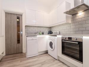 a white kitchen with a washer and dryer at Teylu in Camborne