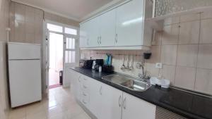 a kitchen with a sink and a white refrigerator at CASA DA AVÓ - Casa típica em Olhão, perto da Marina in Olhão