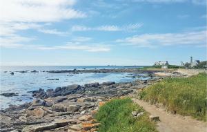 a beach with rocks and the ocean on a cloudy day at Awesome Home In Ploneour Lanvern With 3 Bedrooms And Wifi in Plonéour-Lanvern