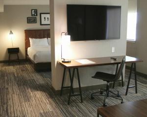 a hotel room with a desk with a bed and a television at Sunbridge Hotel & Conference Centre Sarnia in Sarnia
