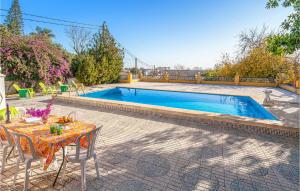 a table and chairs next to a swimming pool at Lovely Home In Tomares With Kitchen in Tomares