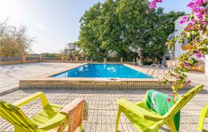 a swimming pool with two chairs and a table at Lovely Home In Tomares With Kitchen in Tomares
