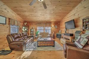 a living room with leather furniture and a flat screen tv at Franklin Cabin with Porch Near Hiking and Waterfalls! in Franklin