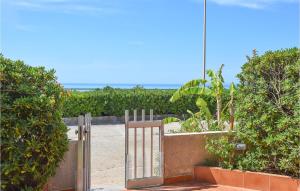 ein offenes Gartentor in einem Garten mit Büschen in der Unterkunft Stunning Apartment In Marina Di Ragusa in Marina di Ragusa