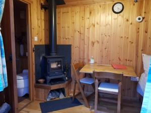 a room with a wood stove and a table and a desk at Beavers Lodge on top of the Shropshire hills in Craven Arms