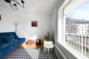 a living room with a blue couch and a large window at Le Boileau - Apartment for 4 people parking and balcony CLOSE to the Lake in Annecy