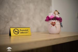 un cartello giallo seduto accanto a un vaso con dei fiori di Piatra Codrilor a Dorna-Arini