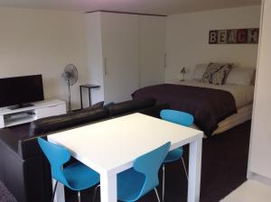 ニュープリマスにあるCentral Park Studioのベッドルーム1室(ベッド1台、テーブル、青い椅子付)