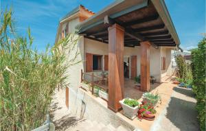 a house with a covered porch with potted plants at Stunning Apartment In Porto Alabe in Magomadas