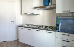 uma cozinha com armários brancos e um forno com placa de fogão em Mari E Monti em Badesi