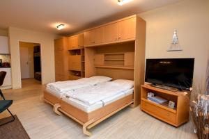 a bedroom with a bed and a flat screen tv at Haus "Panorama" Appartement PAN068 in Duhnen