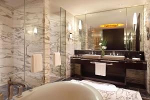 ein Badezimmer mit Badewanne, zwei Waschbecken und einem Spiegel in der Unterkunft The QUBE Hotel Shanghai -Close to Pudong International Airport and Disney Land in Shanghai