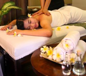 una mujer acostada en una cama de masaje con flores en Metro Hotel Jababeka, en Cikarang