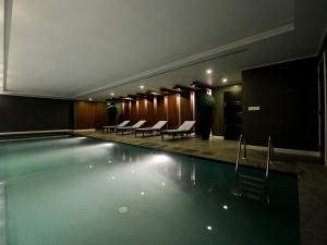 a swimming pool in a building with chairs and tables at The Nishat Hotel in Lahore