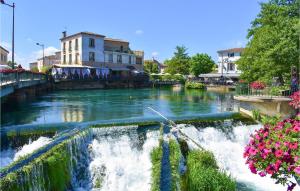 a river with a waterfall in a town with flowers at Nice Apartment In Caumont-Sur-Durance in Caumont-sur-Durance