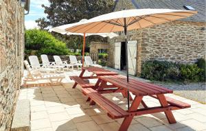 a wooden picnic table with an umbrella on a patio at Beautiful Home In Clohars Carnoet in Clohars-Carnoët