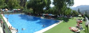 una gran piscina con gente sentada a su alrededor en Apartamento Huerta Grande en Benaocaz