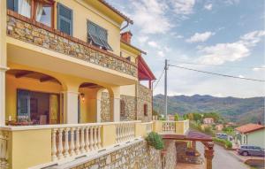 a yellow house with a balcony with mountains in the background at La Perla in Castiglione Chiavarese