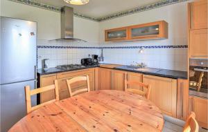 eine Küche mit einem Holztisch und einem Kühlschrank in der Unterkunft Cozy Home In Montchamp With Kitchen in Montchamp