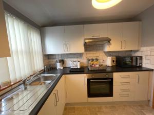 a kitchen with white cabinets and a sink at Westend Holiday Let 3 Brecon in Brecon