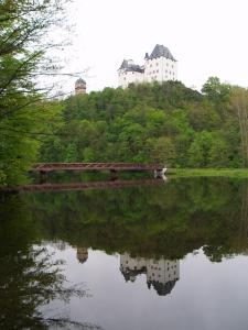 a reflection of a building on a hill next to a lake at Hotel Luginsland in Schleiz