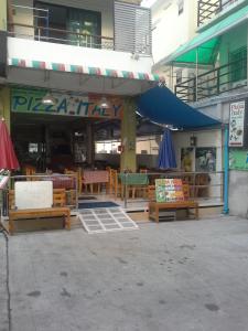 un restaurante con mesas y sombrillas fuera de un edificio en Pizza Italy Restaurant and Guesthouse, en Pattaya central