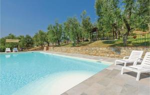 uma piscina com duas cadeiras brancas e uma parede de pedra em Frantoio em Lamporecchio