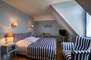 a bedroom with a bed and two chairs at Logis Auberge du Fel in Le Fel