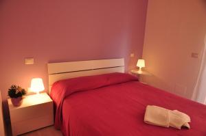 a bedroom with a red bed with red sheets and two lamps at Domus Primavera in Scerne