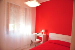 a red bedroom with a bed and a desk and a window at Domus Primavera in Scerne
