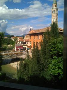 a bridge over a river with a clock tower at Hotel Leon D'Oro in Pieve di Soligo