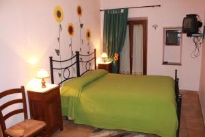a bedroom with a green bed with flowers on the wall at La Loggetta in Bagnoregio