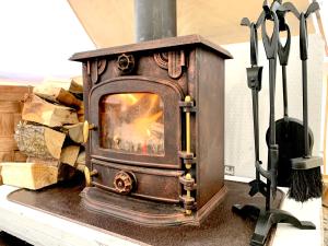 a woodburning stove sitting next to a pile of wood at Karula Stay - Exclusive Glamping Experience with Private Sauna in Ähijärve