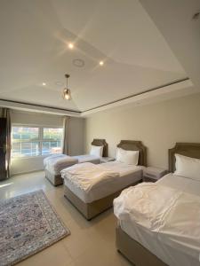 1 dormitorio con 2 camas y alfombra en مزرعة وشاليه سُلافا en Al Ula