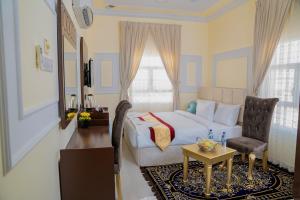 Arkan Al Barzah Hotel Apartment في صور: غرفة نوم بسرير وكرسي وطاولة