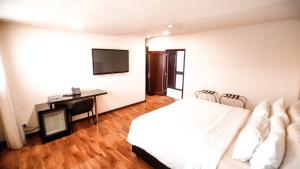 a bedroom with a bed, desk, chair and a television at Hotel Sheridan Corferias Bogotá in Bogotá
