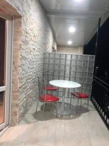 una mesa y cuatro sillas rojas frente a una pared de ladrillo en Villa Gardenia Ureki, en Ureki