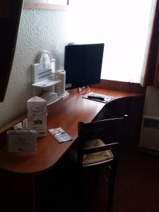 a wooden desk with a computer on top of it at Kyriad Chantilly in Chantilly