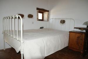 a bedroom with a white bed and a wooden table at Afrodite's House-Restaurated Oil Factory in Ayiá