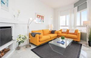 a living room with a yellow couch and a fireplace at Nice Apartment In Calahonda With 2 Bedrooms, Wifi And Outdoor Swimming Pool in Sitio de Calahonda