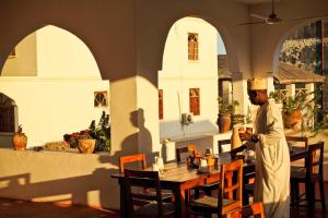 a man standing next to a table in a restaurant at Kiponda B&B in Zanzibar City
