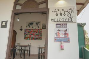 - une porte menant à un restaurant avec un panneau de bienvenue dans l'établissement Lilly Palace Villa Guest House, à Negombo