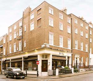 un coche aparcado frente a un gran edificio de ladrillo en 17 Hertford Street, en Londres