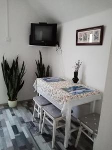 een witte tafel met stoelen en een tv aan de muur bij Mézeskuckó in Tiszaszőlős
