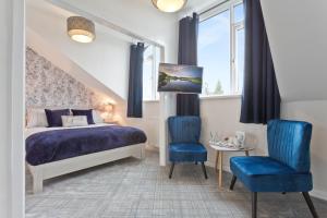a bedroom with a bed and two blue chairs at Broadlands Windermere in Windermere