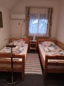 twee bedden in een kamer met een raam bij Mézeskuckó in Tiszaszőlős